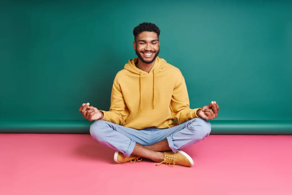 happy african man meditating while sitting against